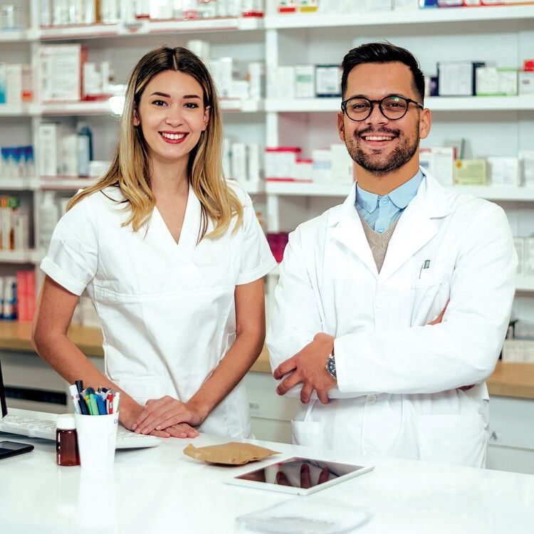 Pharmacist smiling in front of dispensary shelves